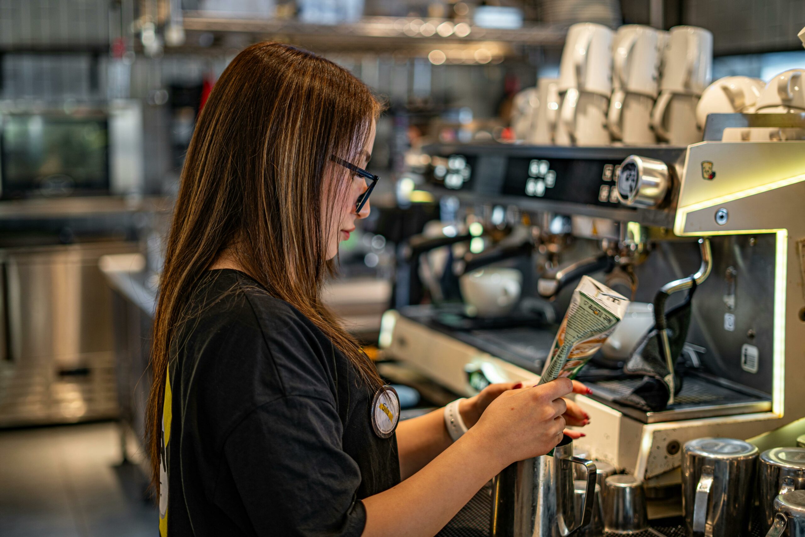 Young barista making coffee at espresso machine in a trendy cafe.